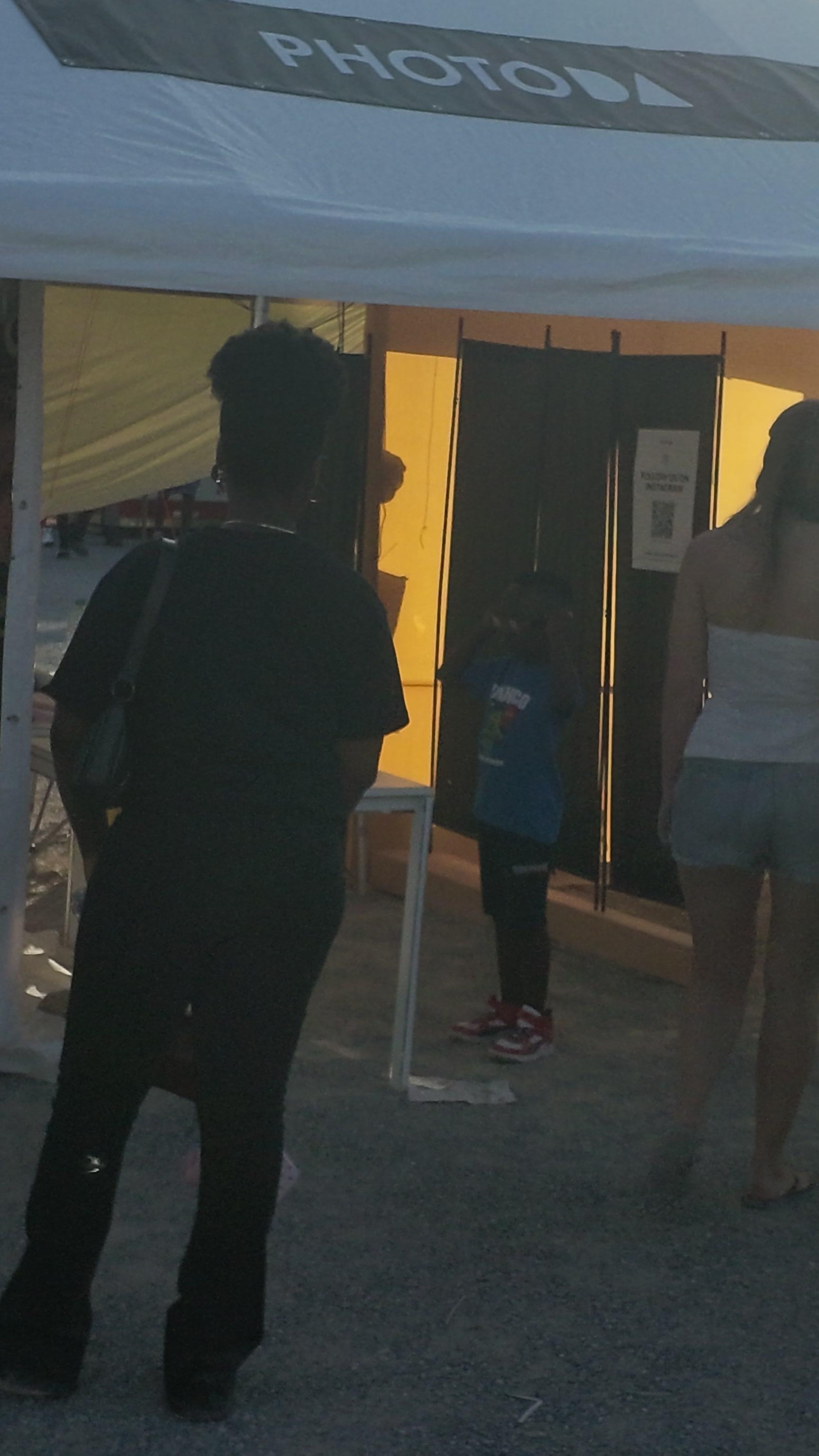 The glowing mirrored entrance of a PhotoDA photo booth at an event, tucked inside a branded tent