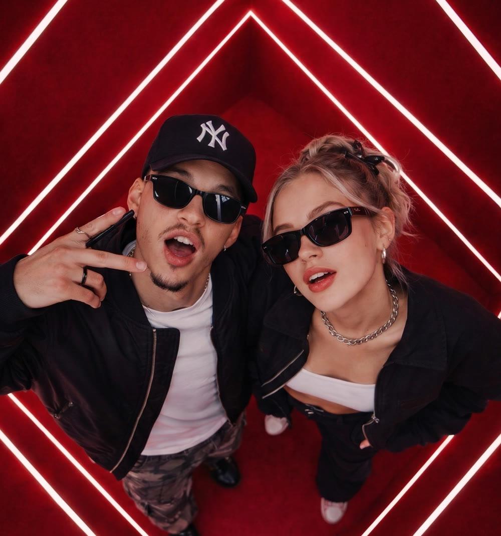 Two friends in an overhead mirror shot inside PhotoDA's Neon Room, red walls lined with glowing white light